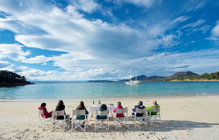 Guests sitting on the beach in Wineglass Bay
