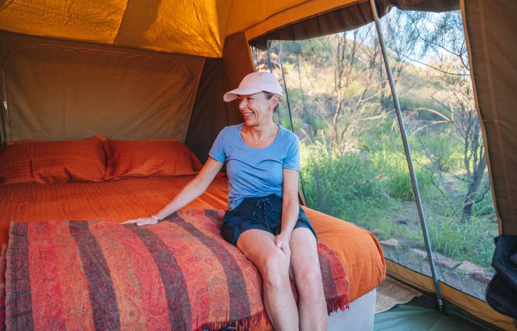 Guest sitting down on bed in sleeping tent