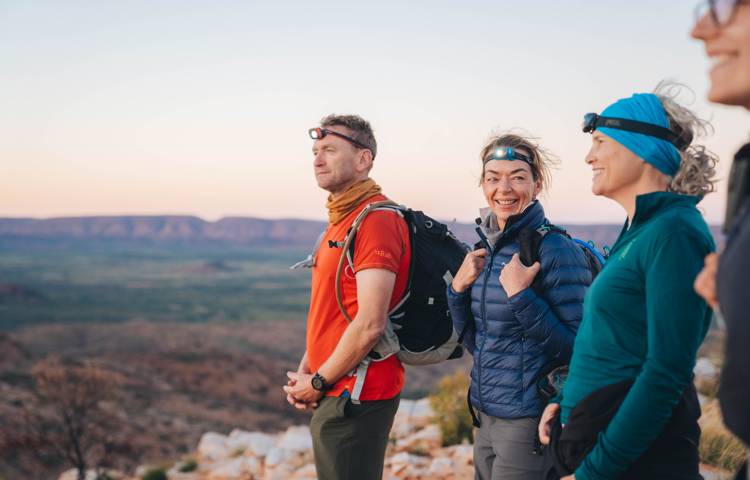 Hikers standing on cliff, enjoying view.