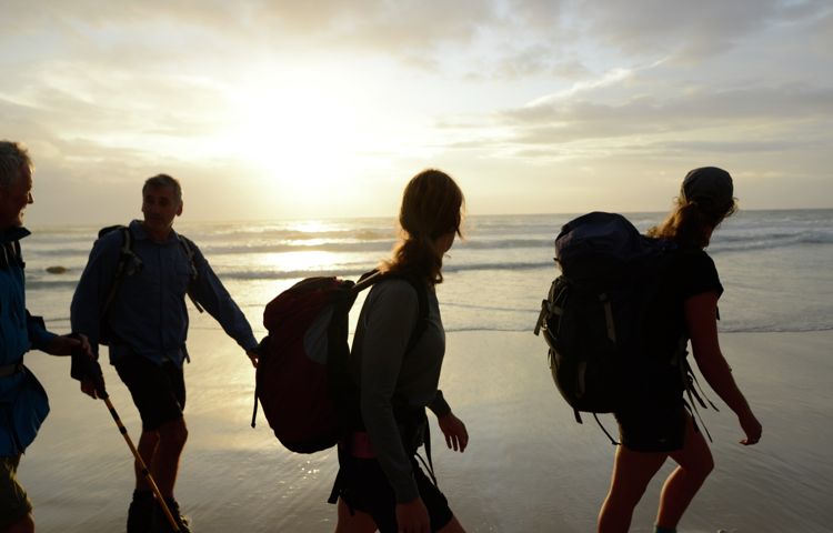 silhouettes of guests walking along Bay of Fires Beach