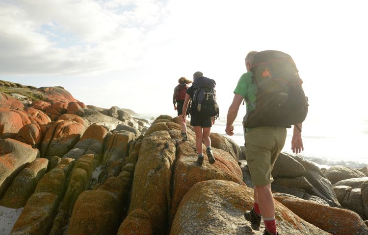 Hikers walking along rocks at Bay of Fires