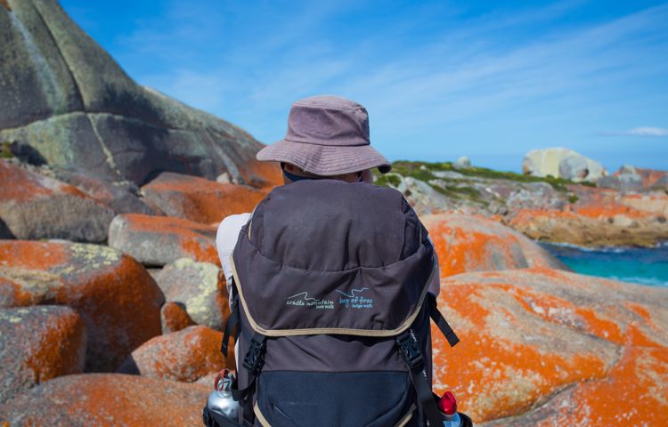 Hikers walking along the rocks at Bay of Fires