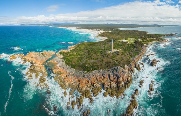 Aerial photo of Bay of Fires rocky coastline and lighthouse