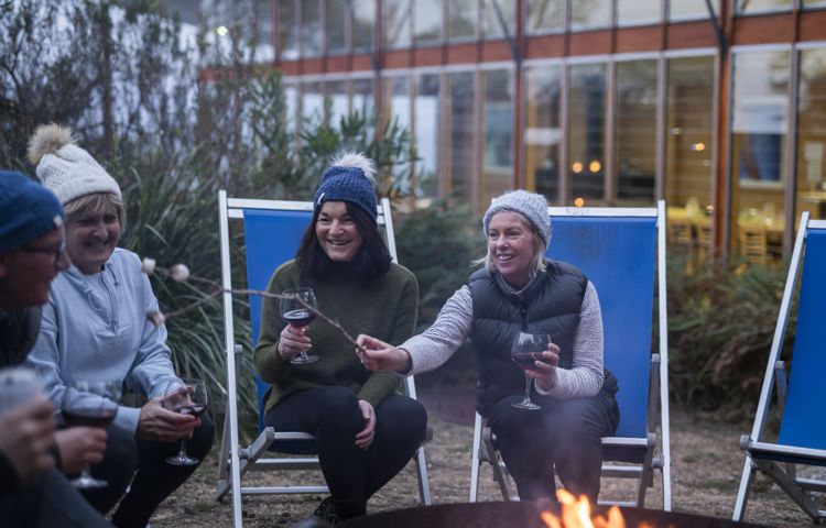 People relaxing and sitting around fire at Bay of Fires