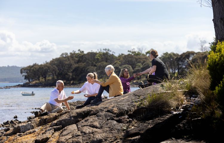Guests sitting on the rocks overlooking the ocean on Bruny Island
